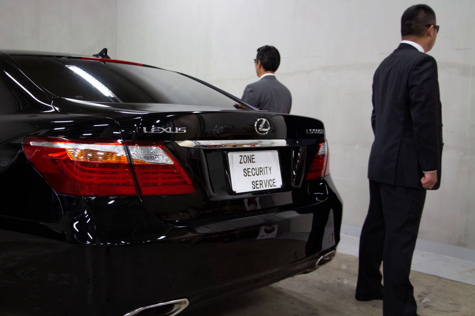 Two suited security personnel beside a vehicle