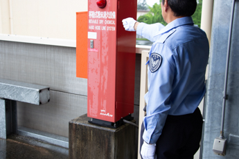 A uniformed Zone officer beside a building fire alarm station