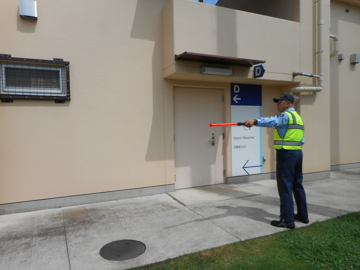 A uniformed Zone officer directing visitors beside a building entrance